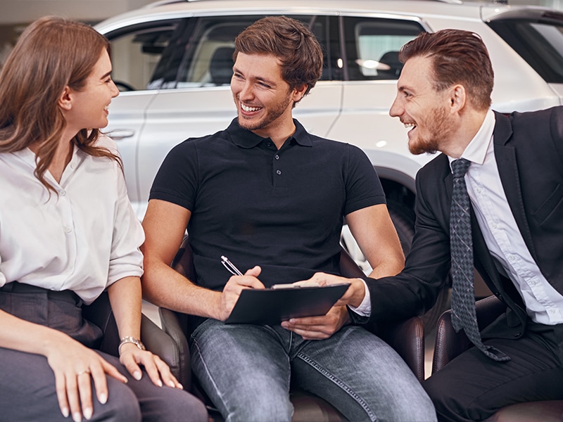 Couple signing up to buy a new white GMC SUV - salesman's happy, too